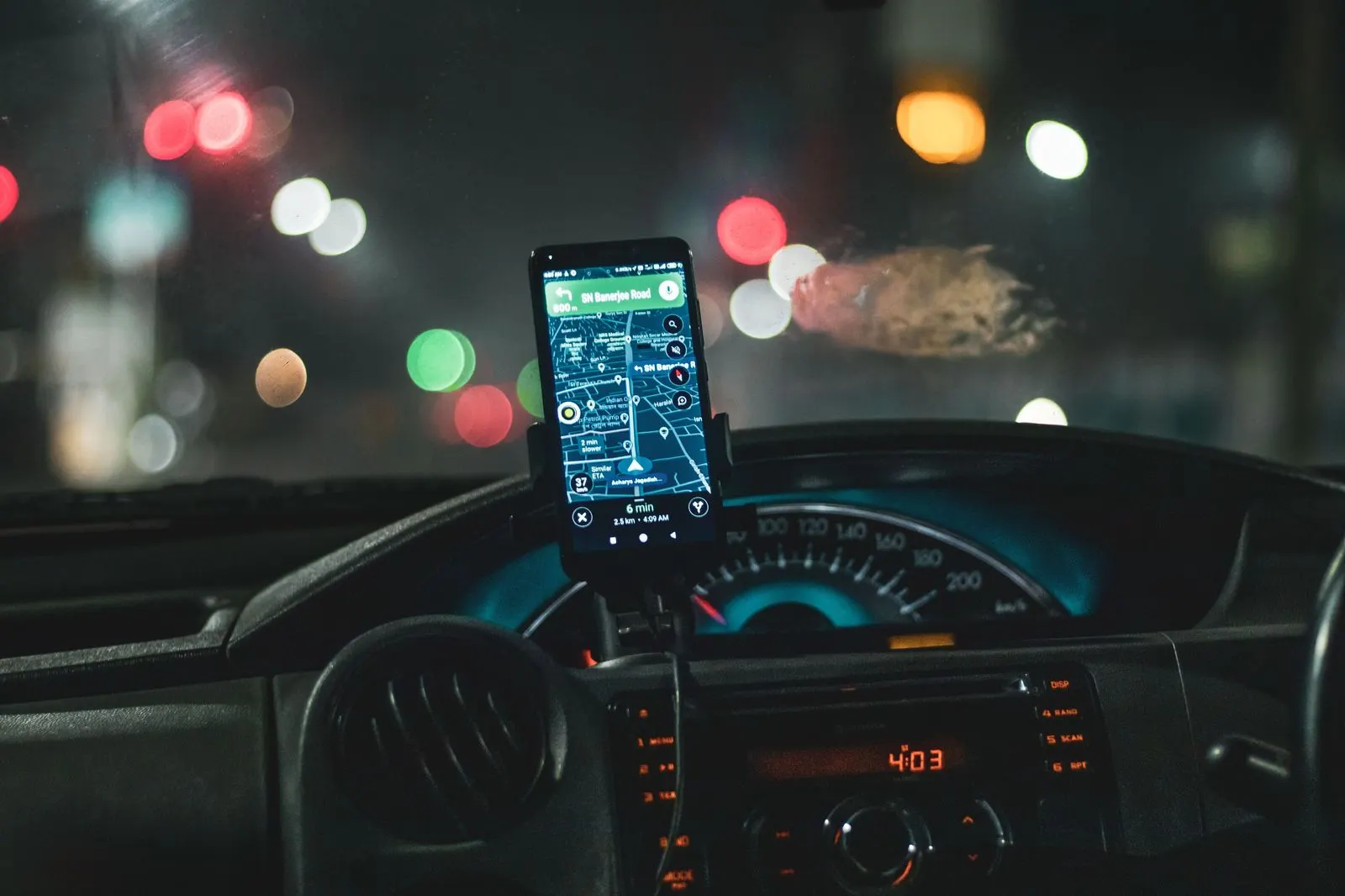 A fixed fare shown on a phone screen beside a chauffeured sedan at an airport kerb
