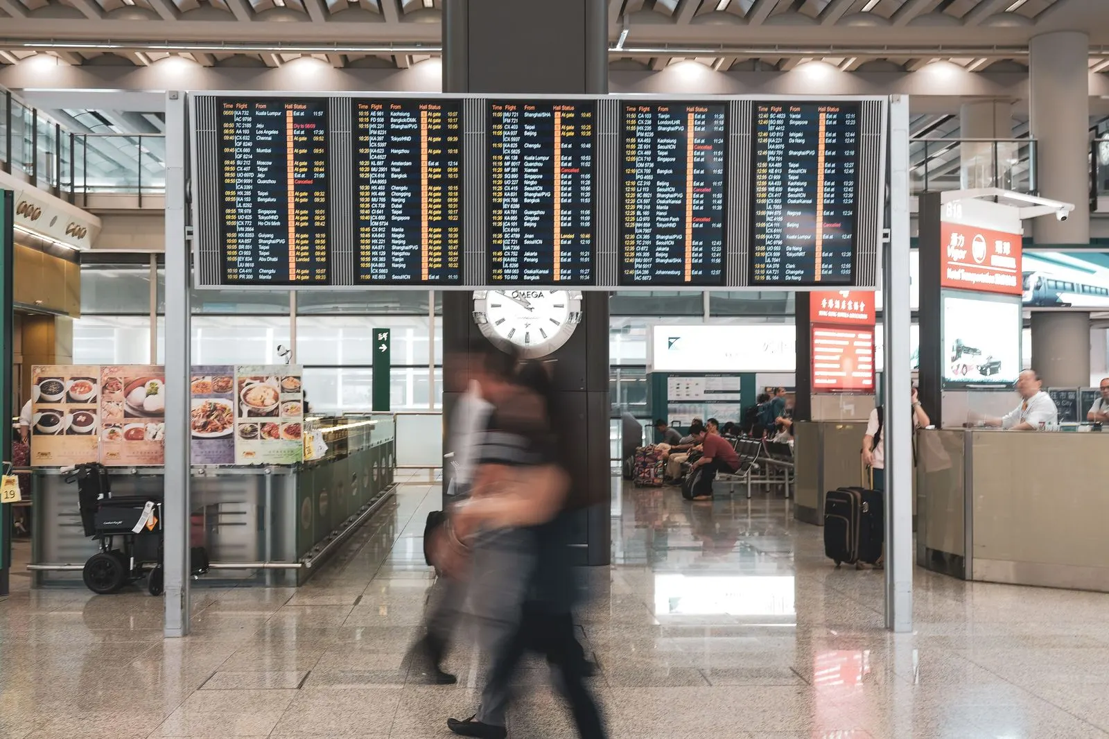 Chauffeur holding a name board at an arrivals hall exit as passengers walk through