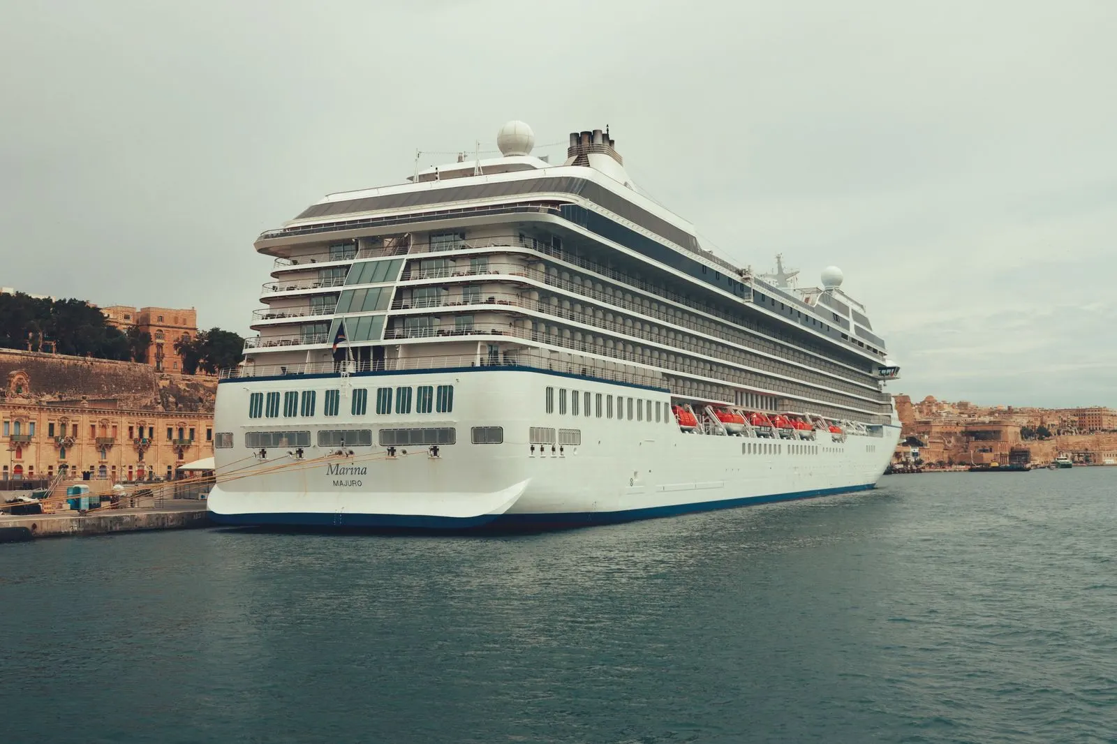 A cruise ship at a terminal with a chauffeured SUV unloading luggage at the porters' station