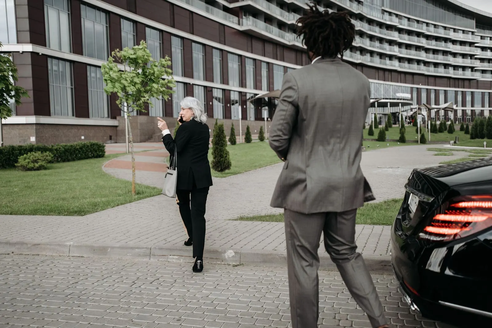 Executive stepping out of a chauffeured sedan at an office tower entrance on a working morning