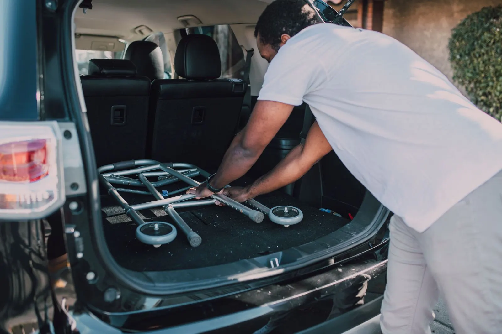 A chauffeur loading luggage into an executive SUV outside a residence in the morning